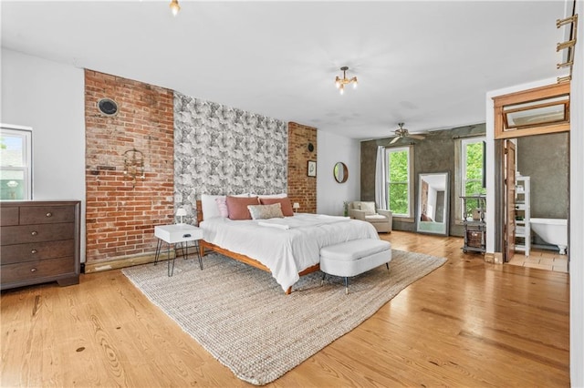 1637 Jefferson St, Kansas City, MO 64108 - bedroom with multiple windows, wood finished floors, an accent wall, and brick wall