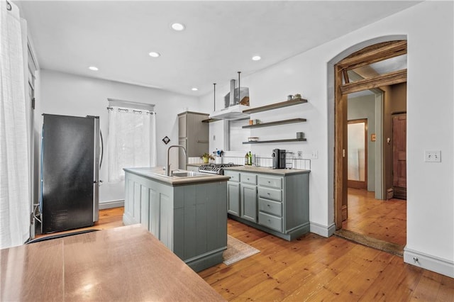 1637 Jefferson St, Kansas City, MO 64108 - kitchen with freestanding refrigerator, wall chimney exhaust hood, light wood-type flooring, gray cabinets, and arched walkways