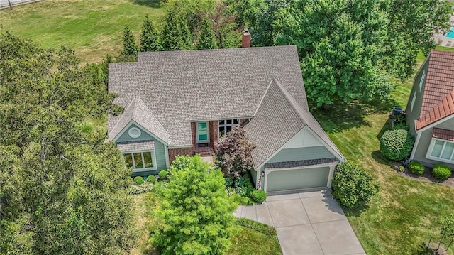 12409 Cambridge Cir, Leawood, KS 66209 - view of front of property featuring concrete driveway, a garage, a chimney, and a front yard