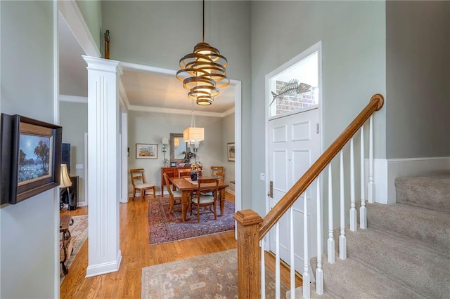 12409 Cambridge Cir, Leawood, KS 66209 - entryway with light wood finished floors, a chandelier, ornamental molding, a towering ceiling, and decorative columns
