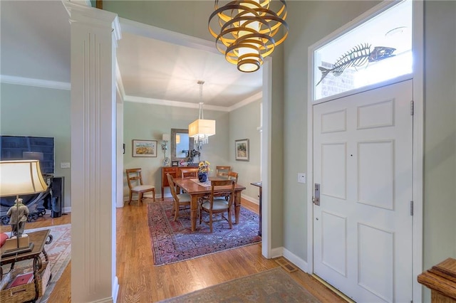 12409 Cambridge Cir, Leawood, KS 66209 - foyer entrance featuring decorative columns, ornamental molding, wood finished floors, and a chandelier