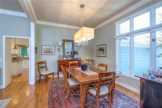 12409 Cambridge Cir, Leawood, KS 66209 - dining room with crown molding, light wood finished floors, plenty of natural light, and a chandelier