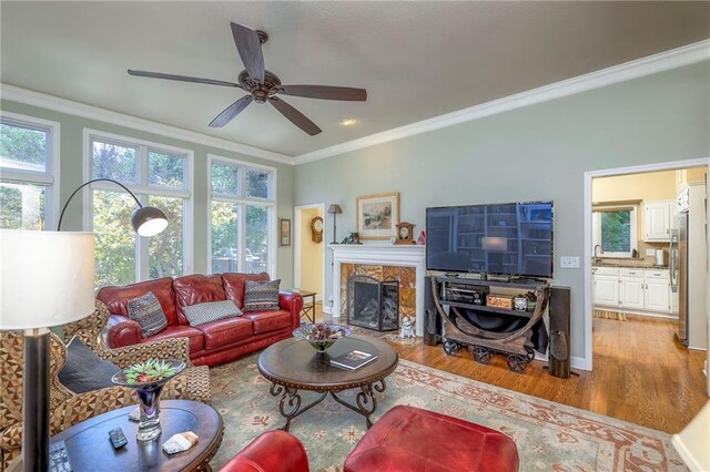 12409 Cambridge Cir, Leawood, KS 66209 - living area with light wood finished floors, crown molding, plenty of natural light, a ceiling fan, and a fireplace
