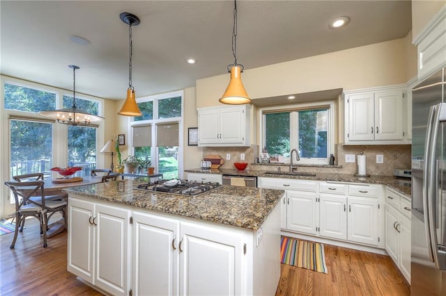 12409 Cambridge Cir, Leawood, KS 66209 - kitchen featuring appliances with stainless steel finishes, a center island, light wood-style flooring, decorative backsplash, and recessed lighting