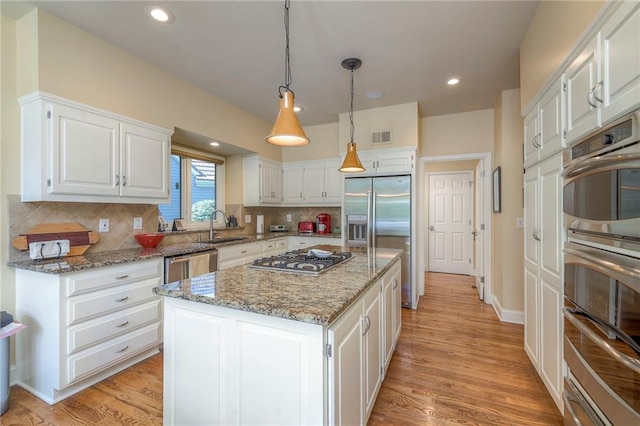 12409 Cambridge Cir, Leawood, KS 66209 - kitchen with appliances with stainless steel finishes, white cabinetry, light stone countertops, light wood-style floors, and recessed lighting