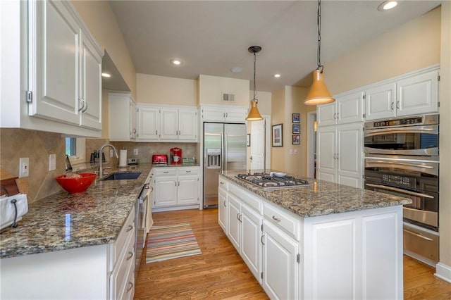 12409 Cambridge Cir, Leawood, KS 66209 - kitchen with stainless steel appliances, a kitchen island, light wood-style flooring, white cabinetry, and recessed lighting