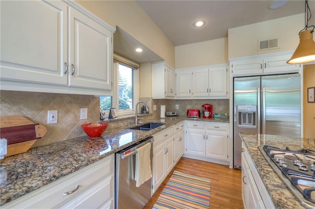 12409 Cambridge Cir, Leawood, KS 66209 - kitchen featuring stainless steel appliances, white cabinets, stone counters, light wood-style flooring, and tasteful backsplash