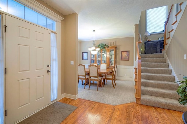 1105 Blazing Star Dr, Lees Summit, MO 64081 - foyer entrance with stairs, a chandelier, crown molding, light wood-style flooring, and a wainscoted wall