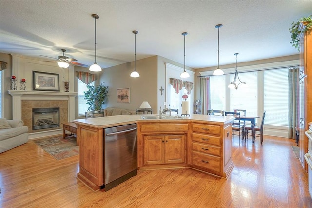 1105 Blazing Star Dr, Lees Summit, MO 64081 - kitchen featuring stainless steel dishwasher, light wood finished floors, decorative light fixtures, open floor plan, and a tiled fireplace