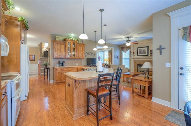 1105 Blazing Star Dr, Lees Summit, MO 64081 - kitchen featuring white appliances, brown cabinets, a kitchen bar, light wood finished floors, and light countertops