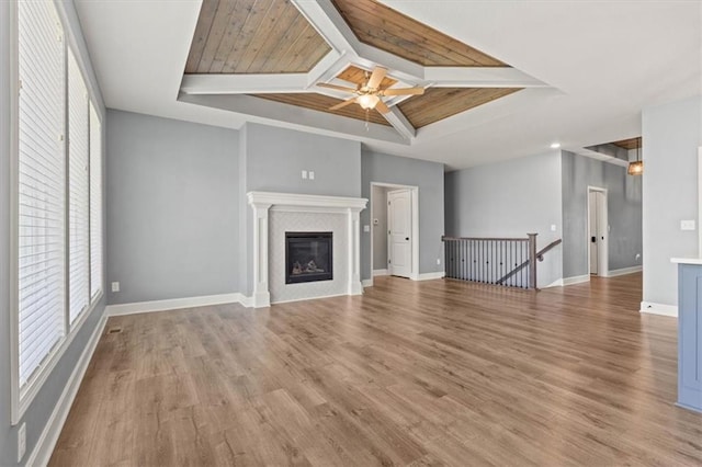 12421 Meadow Ln, Kansas City, KS 66109 - unfurnished living room featuring plenty of natural light, ceiling fan, light wood finished floors, a wooden ceiling with exposed beams, and a glass covered fireplace