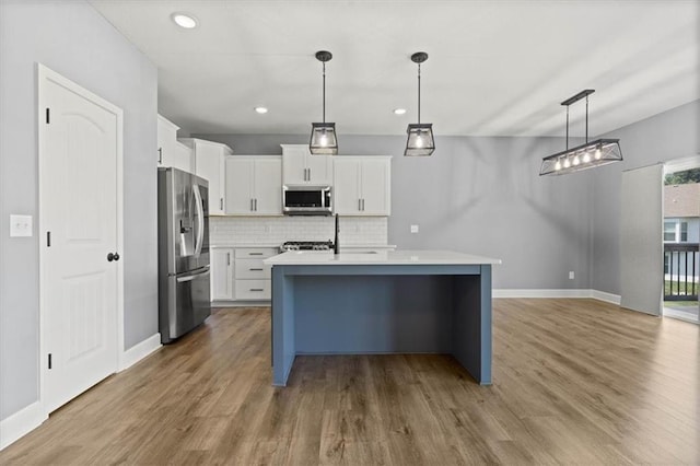 12421 Meadow Ln, Kansas City, KS 66109 - kitchen with stainless steel appliances, light countertops, decorative backsplash, wood finished floors, and white cabinetry
