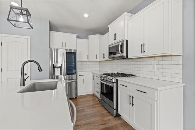 12421 Meadow Ln, Kansas City, KS 66109 - kitchen with appliances with stainless steel finishes, dark wood-style floors, tasteful backsplash, white cabinets, and recessed lighting