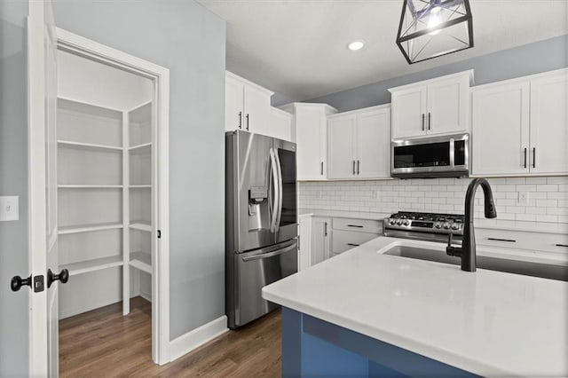 12421 Meadow Ln, Kansas City, KS 66109 - kitchen featuring appliances with stainless steel finishes, dark wood-type flooring, tasteful backsplash, white cabinetry, and light countertops