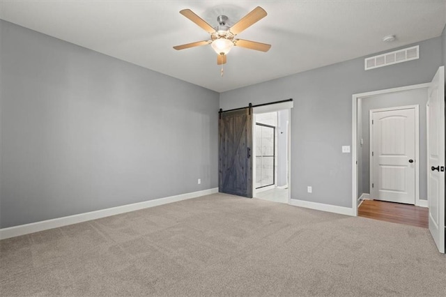 12421 Meadow Ln, Kansas City, KS 66109 - unfurnished bedroom featuring carpet, a barn door, and ceiling fan