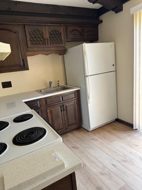 5737 Metcalf Ct, Overland Park, KS 66202 - kitchen with white appliances, light countertops, dark brown cabinets, light wood finished floors, and backsplash
