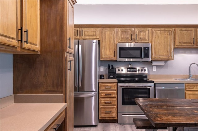 632 SW Shadow Glen Ct, Blue Springs, MO 64015 - kitchen featuring appliances with stainless steel finishes, light countertops, wood finished floors, and brown cabinetry