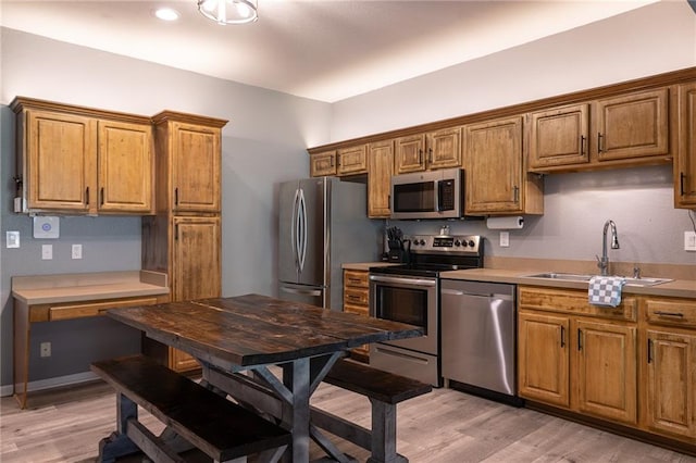 632 SW Shadow Glen Ct, Blue Springs, MO 64015 - kitchen with stainless steel appliances, light wood-style floors, brown cabinets, and light countertops