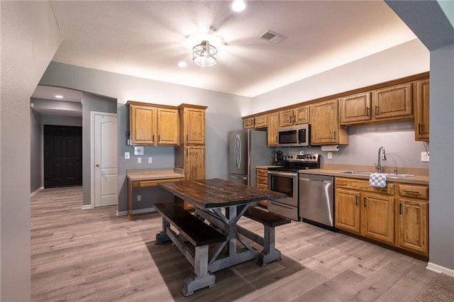 632 SW Shadow Glen Ct, Blue Springs, MO 64015 - kitchen with stainless steel appliances, brown cabinets, light wood finished floors, light countertops, and arched walkways