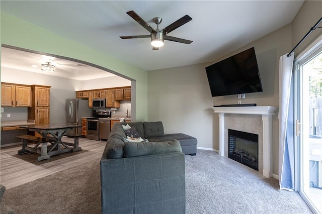 632 SW Shadow Glen Ct, Blue Springs, MO 64015 - living room with a ceiling fan, a fireplace, light colored carpet, and arched walkways