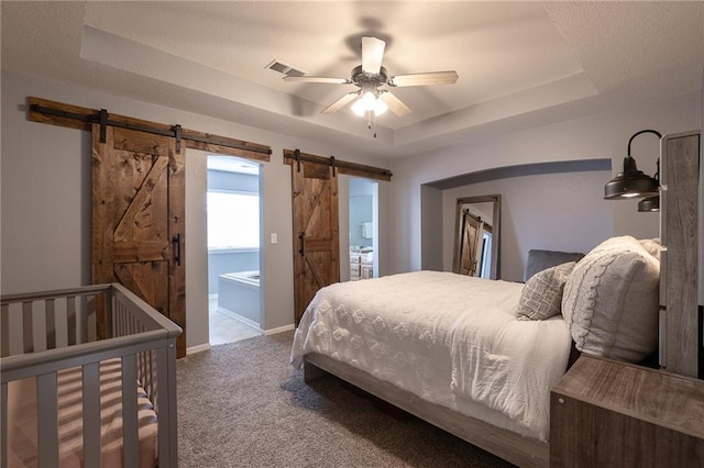 632 SW Shadow Glen Ct, Blue Springs, MO 64015 - bedroom with a barn door, a tray ceiling, carpet floors, and a ceiling fan