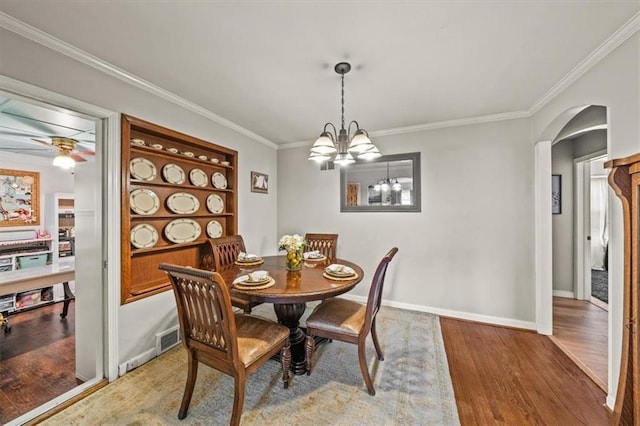 1115 W 26th St S, Independence, MO 64052 - dining space featuring arched walkways, wood finished floors, crown molding, and a chandelier