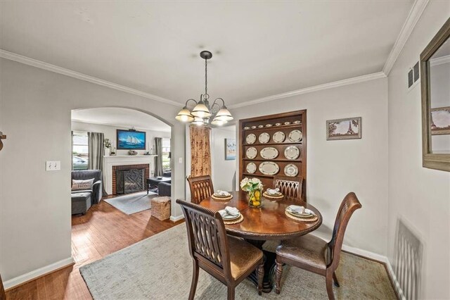 1115 W 26th St S, Independence, MO 64052 - dining room featuring arched walkways, ornamental molding, a fireplace, and wood finished floors