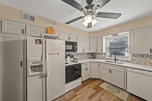 1115 W 26th St S, Independence, MO 64052 - kitchen featuring white appliances, decorative backsplash, light countertops, white cabinetry, and light wood-style flooring