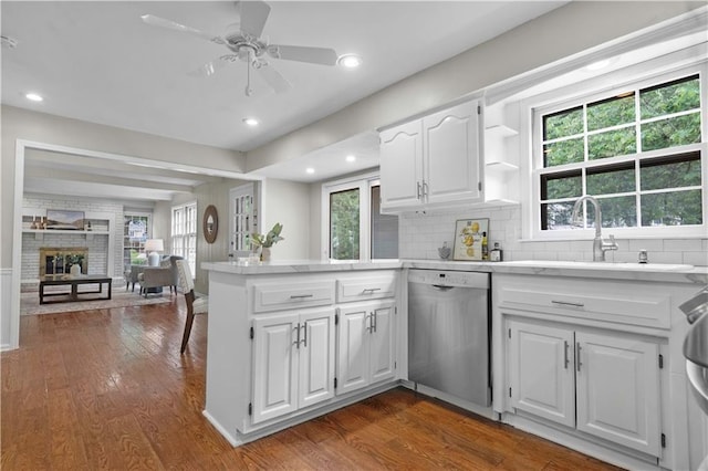 7710 Noland Rd, Lenexa, KS 66216 - kitchen featuring stainless steel dishwasher, a peninsula, light countertops, dark wood-type flooring, and a fireplace