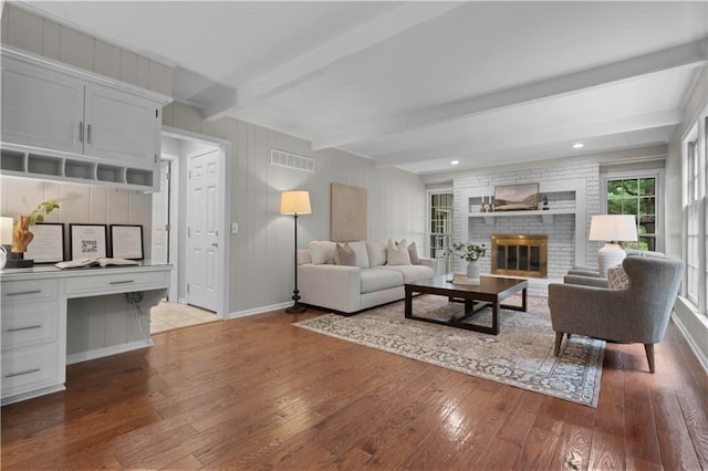 7710 Noland Rd, Lenexa, KS 66216 - living room with hardwood / wood-style floors, beam ceiling, and a brick fireplace