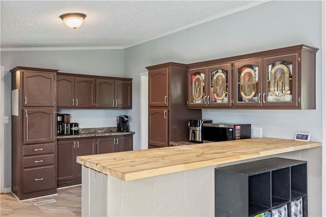 679 Kingman Rd, Pomona, KS 66076 - kitchen with a textured ceiling, ornamental molding, butcher block counters, glass insert cabinets, and a peninsula