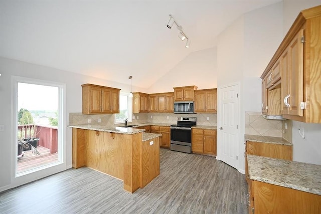 12905 Ridgeview Dr, Platte City, MO 64079 - kitchen featuring stainless steel appliances, a peninsula, brown cabinets, light wood-type flooring, and high vaulted ceiling