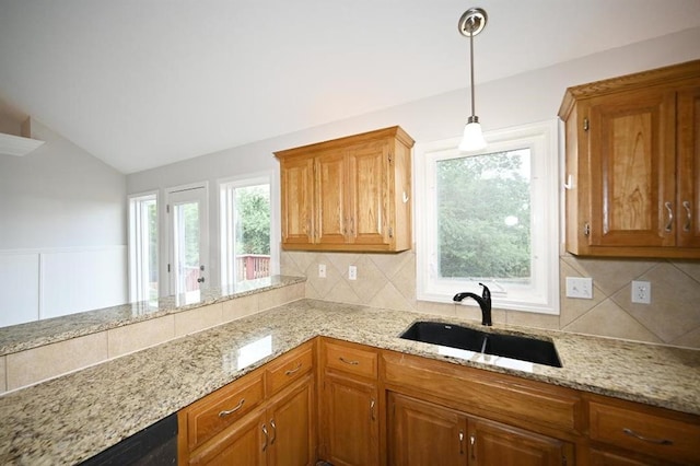 12905 Ridgeview Dr, Platte City, MO 64079 - kitchen featuring vaulted ceiling, light stone counters, backsplash, and brown cabinetry