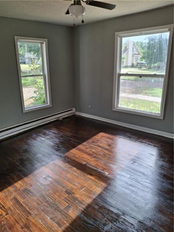 608 N Cedar St, Ottawa, KS 66067 - unfurnished room featuring baseboard heating, plenty of natural light, dark wood-style flooring, a ceiling fan, and a textured ceiling