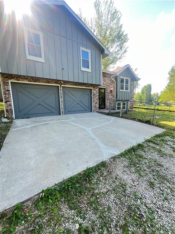 14948 Lakeside Dr, Excelsior Springs, MO 64024 - view of side of property featuring a garage, board and batten siding, concrete driveway, and brick siding