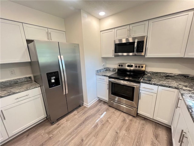 14948 Lakeside Dr, Excelsior Springs, MO 64024 - kitchen with appliances with stainless steel finishes, light wood finished floors, white cabinets, dark stone countertops, and recessed lighting