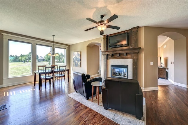 10963 S Carbondale St, Olathe, KS 66061 - living area with arched walkways, a textured ceiling, dark wood-style floors, ceiling fan, and a fireplace