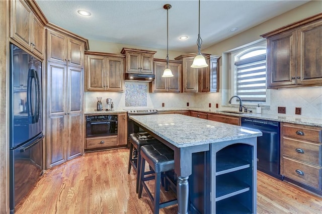 10963 S Carbondale St, Olathe, KS 66061 - kitchen with black appliances, under cabinet range hood, a kitchen island, light wood-style floors, and recessed lighting