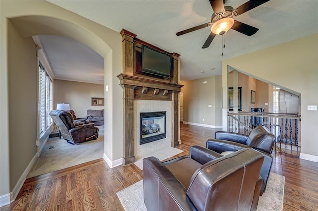 10963 S Carbondale St, Olathe, KS 66061 - living area with a ceiling fan, wood finished floors, arched walkways, and a tiled fireplace