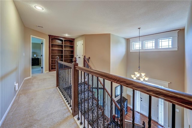 10963 S Carbondale St, Olathe, KS 66061 - corridor featuring a chandelier, an upstairs landing, a textured ceiling, built in shelves, and light carpet