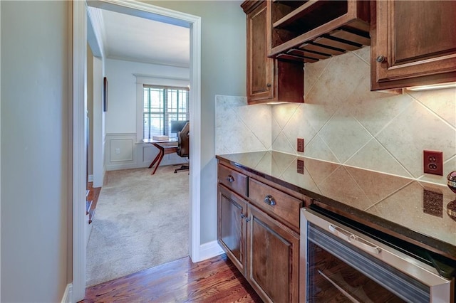 10963 S Carbondale St, Olathe, KS 66061 - kitchen featuring beverage cooler, backsplash, light wood-type flooring, dark countertops, and a wainscoted wall