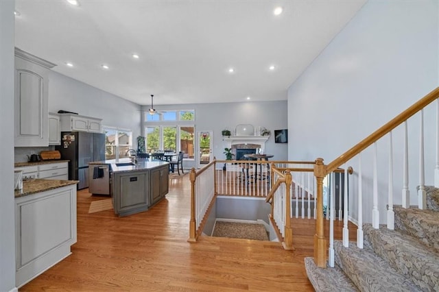 2312 SW Post Oak Ct, Lees Summit, MO 64082 - kitchen with appliances with stainless steel finishes, light wood-type flooring, recessed lighting, a fireplace, and a center island with sink