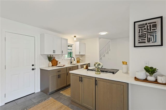 3029 S 9th Pl, Kansas City, KS 66103 - kitchen with stovetop, light countertops, white cabinets, and backsplash