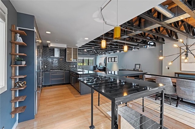 1303 W 47th St, Kansas City, MO 64112 - kitchen featuring tasteful backsplash, light wood finished floors, wall chimney exhaust hood, dark countertops, and recessed lighting
