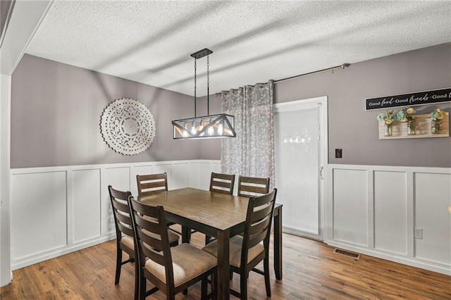 17507 E 35th Ter, Independence, MO 64055 - dining room with a decorative wall, wood finished floors, wainscoting, a textured ceiling, and a chandelier