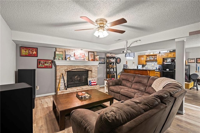 17507 E 35th Ter, Independence, MO 64055 - living area featuring a ceiling fan, a textured ceiling, light wood-type flooring, bar, and a brick fireplace