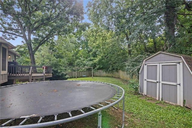 17507 E 35th Ter, Independence, MO 64055 - fenced backyard featuring a trampoline, a storage unit, a wooden deck, and view of scattered trees