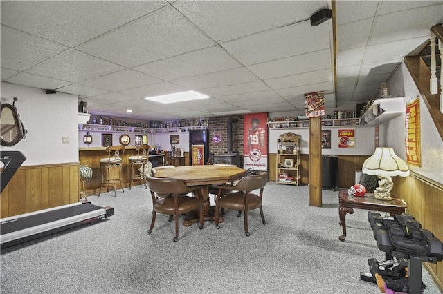 2005 NW Fawn Dr, Blue Springs, MO 64015 - carpeted dining space with a wood stove, a paneled ceiling, a bar, wood walls, and wainscoting