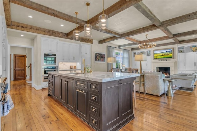 10400 Howe Dr, Leawood, KS 66206 - kitchen featuring light wood-style floors, white cabinets, beamed ceiling, a chandelier, and decorative light fixtures