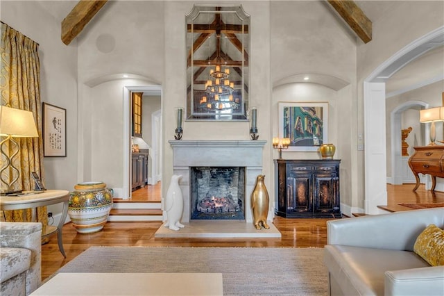 10400 Howe Dr, Leawood, KS 66206 - living area featuring arched walkways, beam ceiling, wood finished floors, high vaulted ceiling, and a lit fireplace